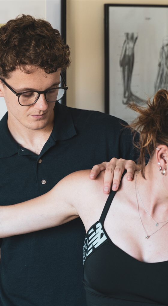 A Solution Clinic therapist assessing a client's shoulder and scapula