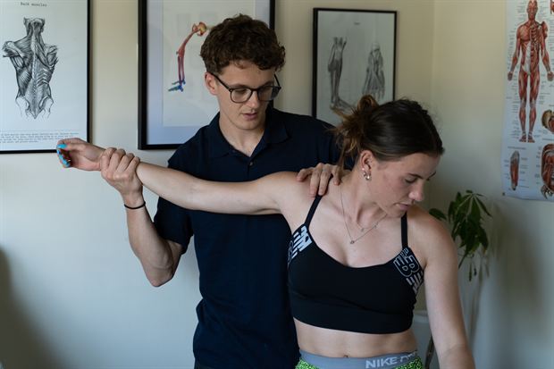 A therapist assessing a client's shoulder movement